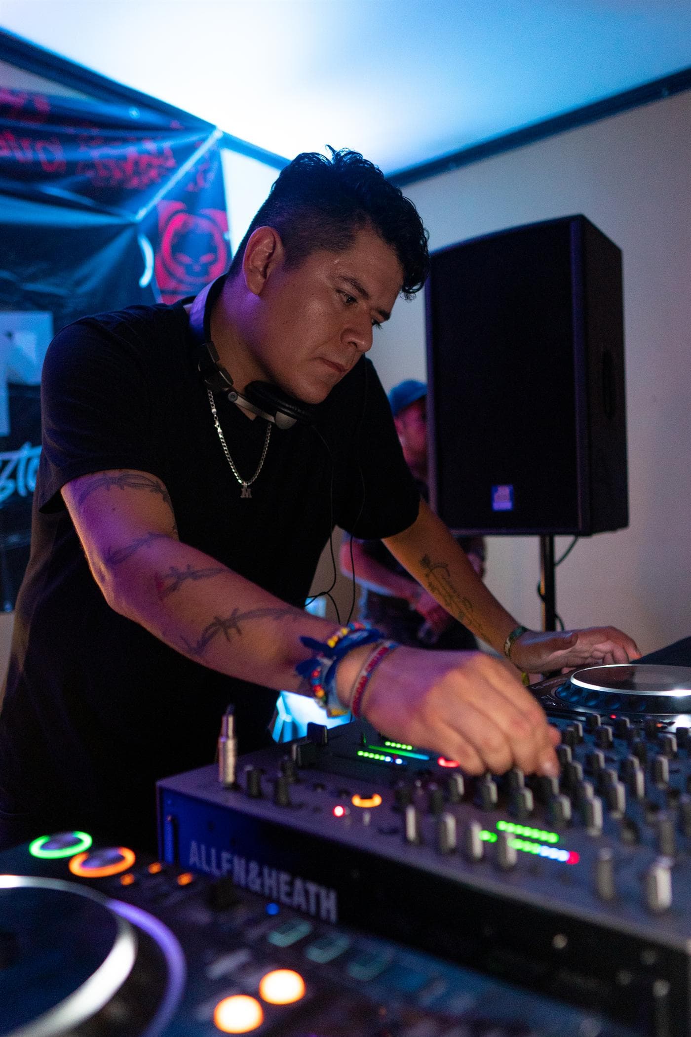 Miguel concentrado en el mixer Allen & Heath, con audífonos al cuello